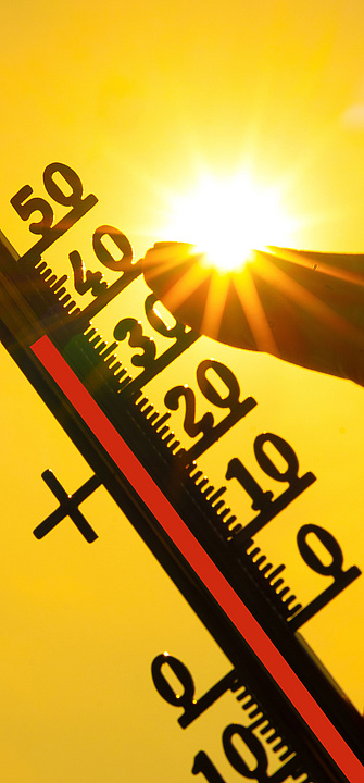 Eine Hand hält ein klassisches Thermometer, das +40 Grad Celsius anzeigt, gegen die Sonne.