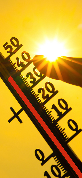Eine Hand hält ein klassisches Thermometer, das +40 Grad Celsius anzeigt, gegen die Sonne.