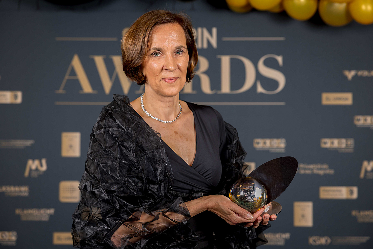 Elke Fröhlich-Reiterer steht in einem schwarzen Abendkleid vor einer Sponsoren wandpräsentiert ihren Steierin-Award