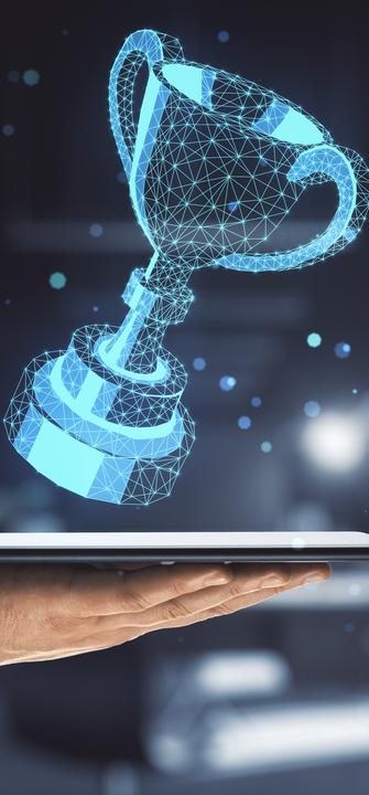 Eine Hand hält ein Tablet über dem ein 3D-Hologramm eines Pokals schwebt