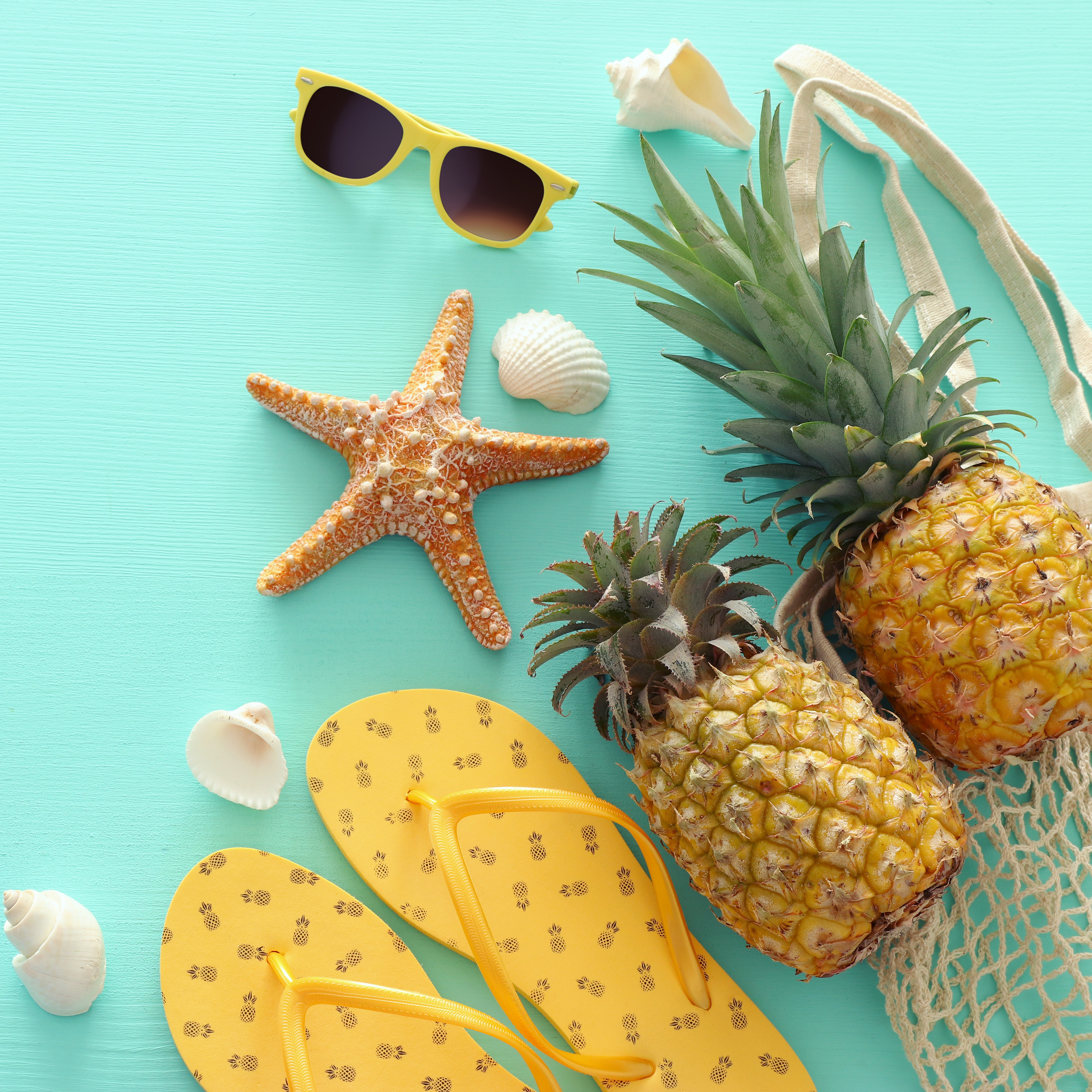 Ananas und Strand-Accessoires auf pastellfarbenem Mint