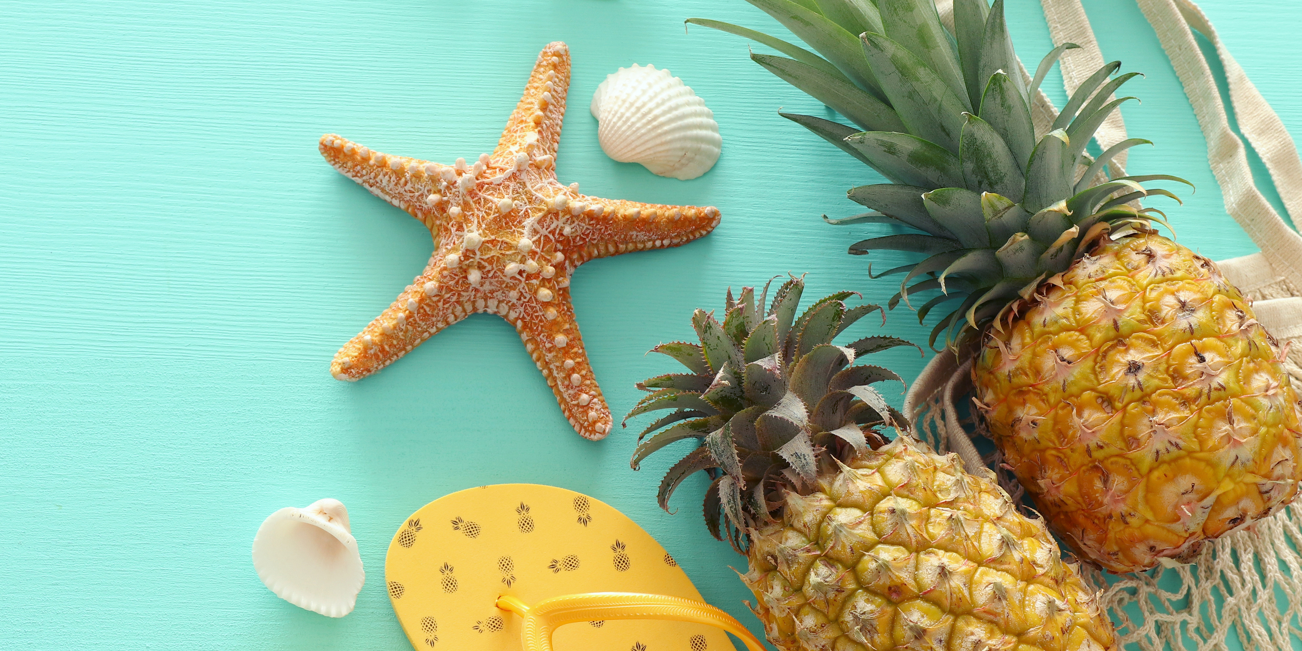 Ananas und Strand-Accessoires auf pastellfarbenem Mint