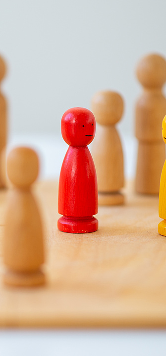 Holzfiguren auf Spielfeld als Symbol für systemische Therapie, Familientherapie