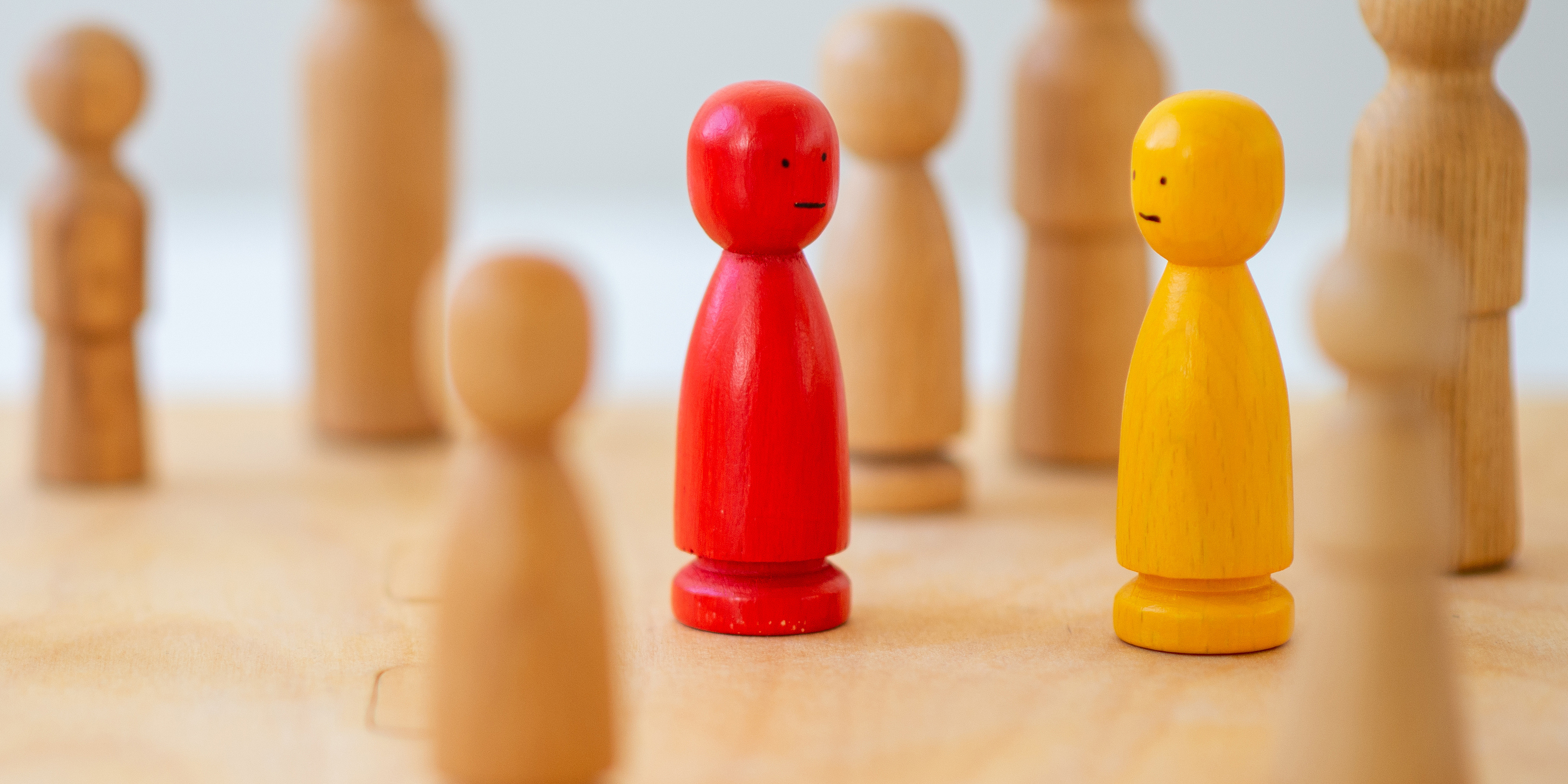 Holzfiguren auf Spielfeld als Symbol für systemische Therapie, Familientherapie