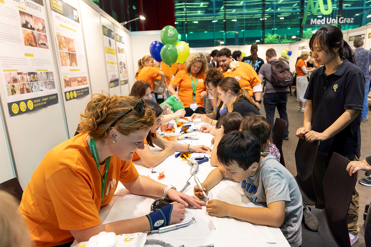 Eine Mitarbeiterin und ein Kind bei einer Mitmachstation bei der Langen Nacht der Forschung