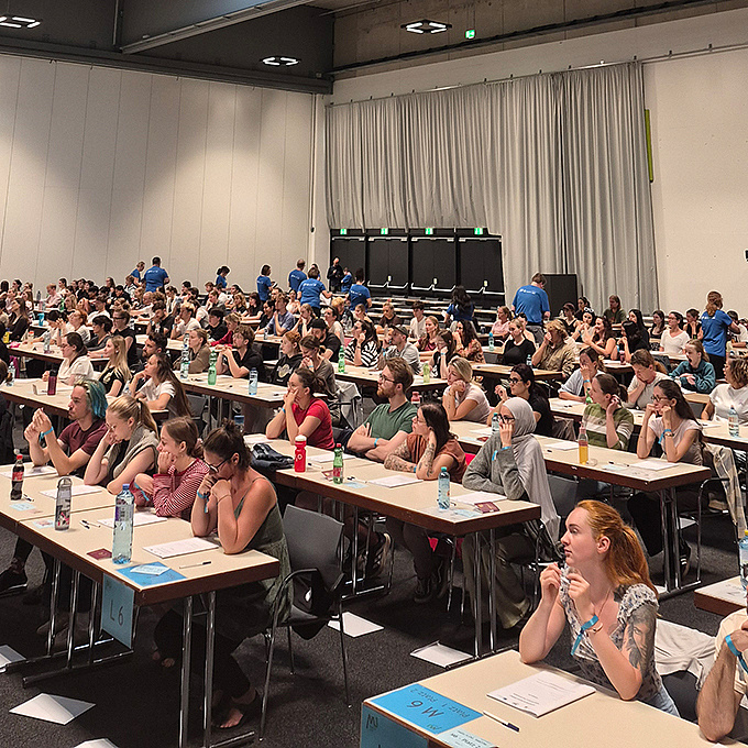 Die Studienwerber*innen für das Psychotherapiestudium sitzen in der Grazer Stadthalle und warten auf den Start des Tests.