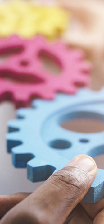 Hände mit bunten Zahnrädern