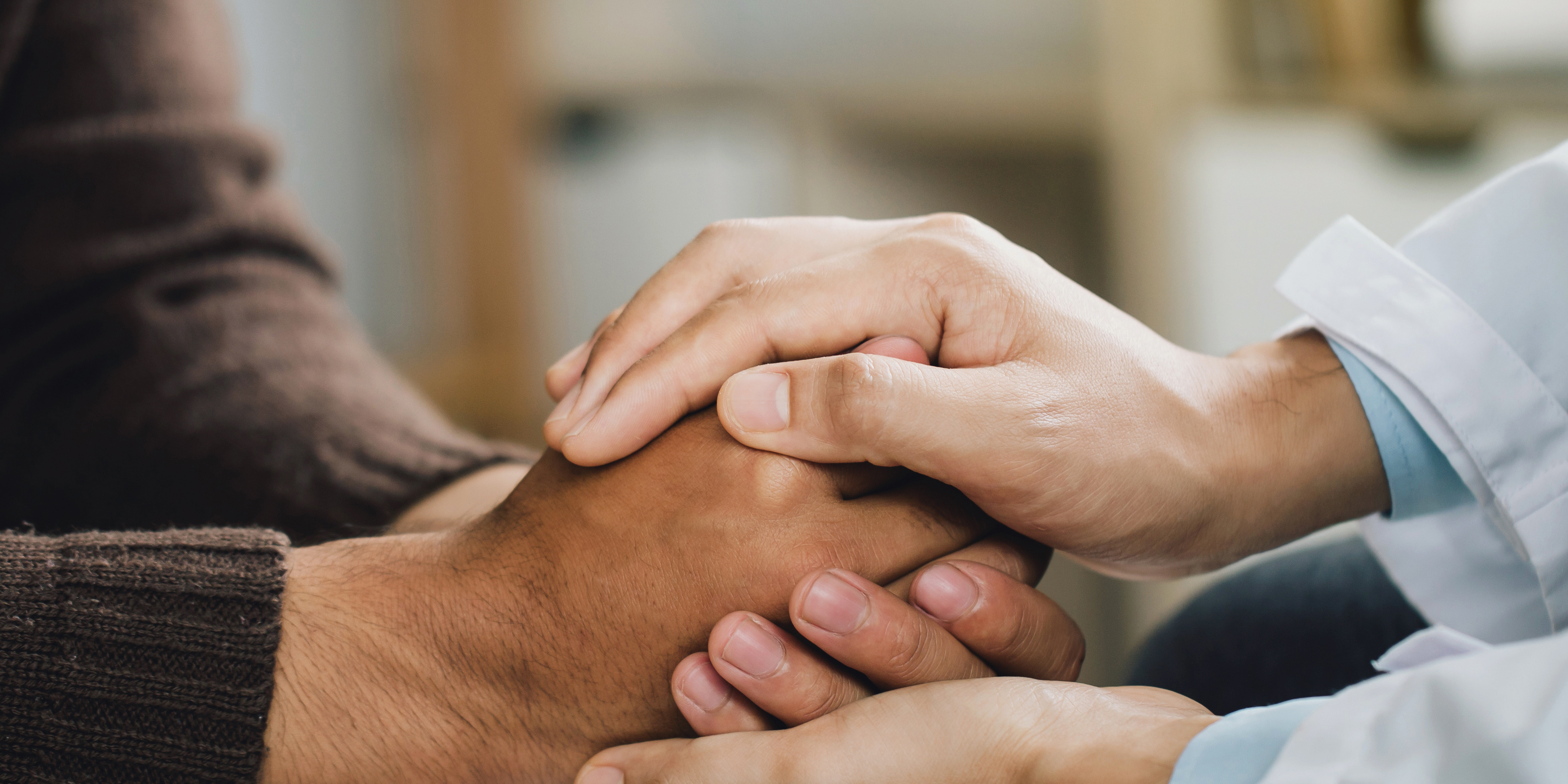 Ein Psychiater hält die Hände eines Patienten fest