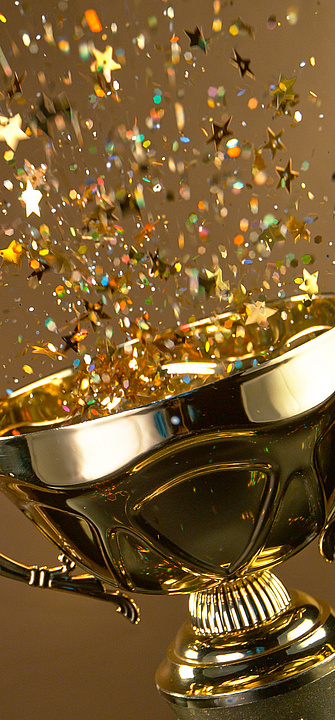 Ein Pokal aus dem Confetti sprüht auf goldenem Hintergrund
