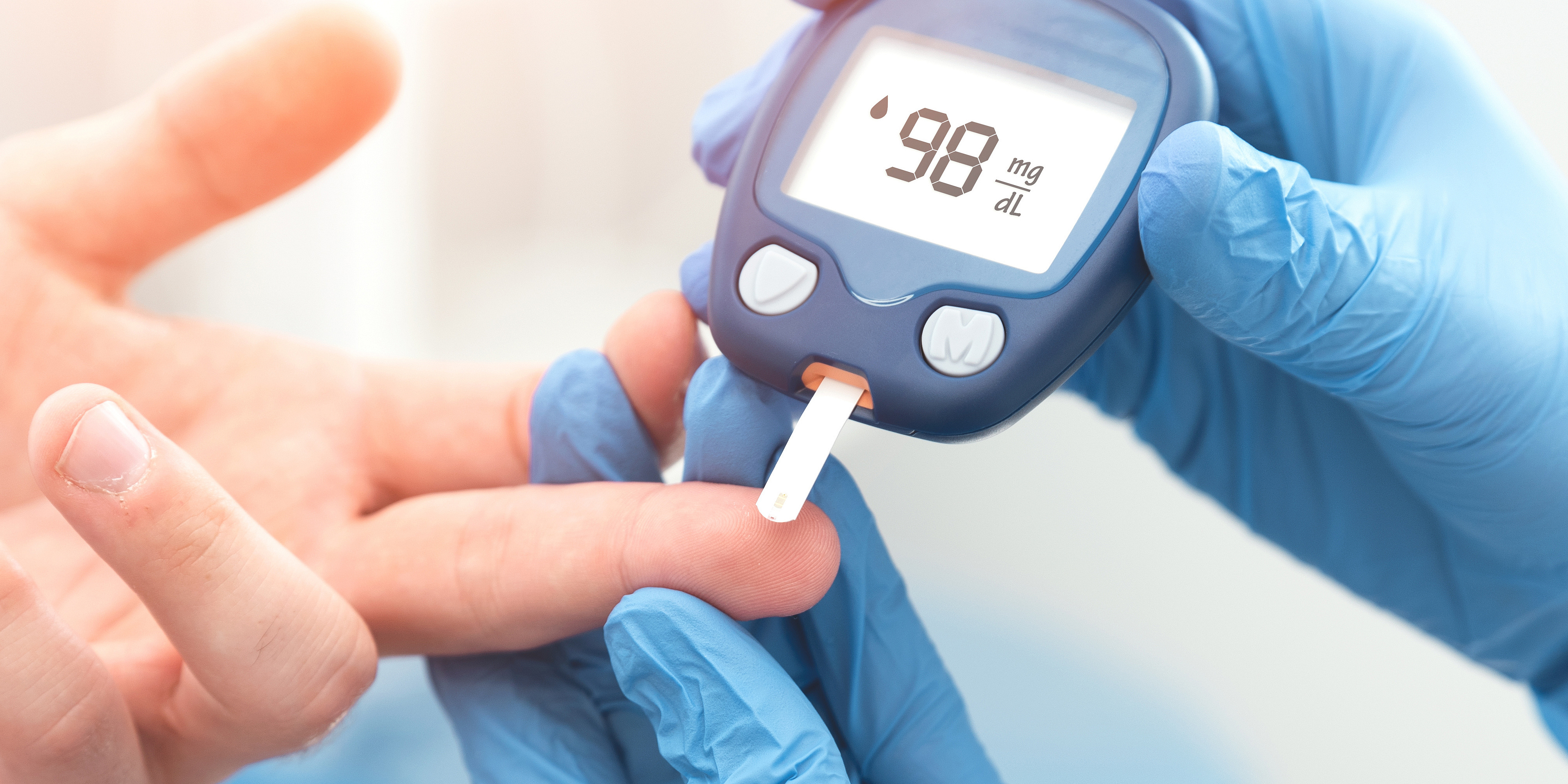 Arzt überprüft Blutzuckerspiegel mit Blutzuckermessgerät