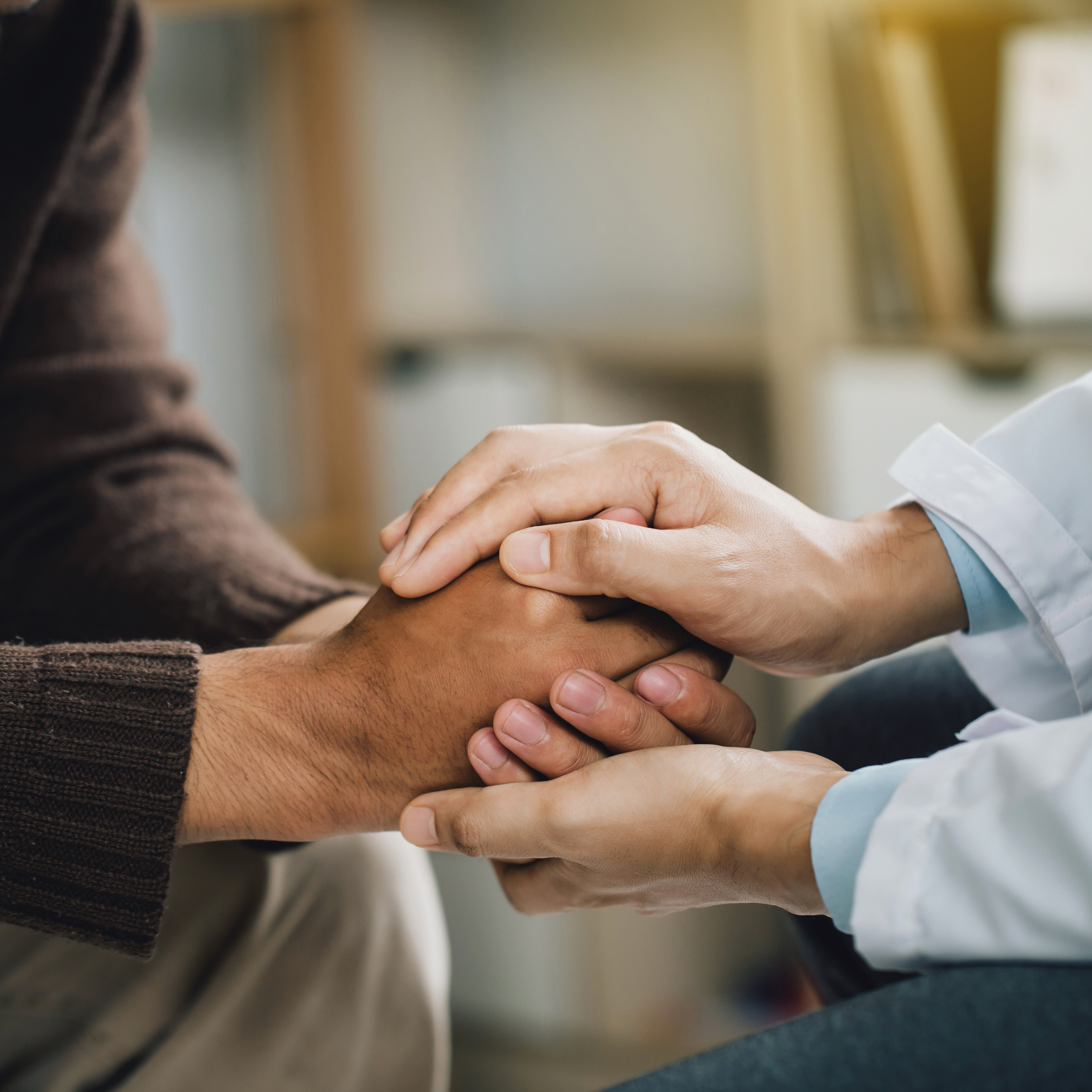 Ein Psychiater hält die Hände eines Patienten fest