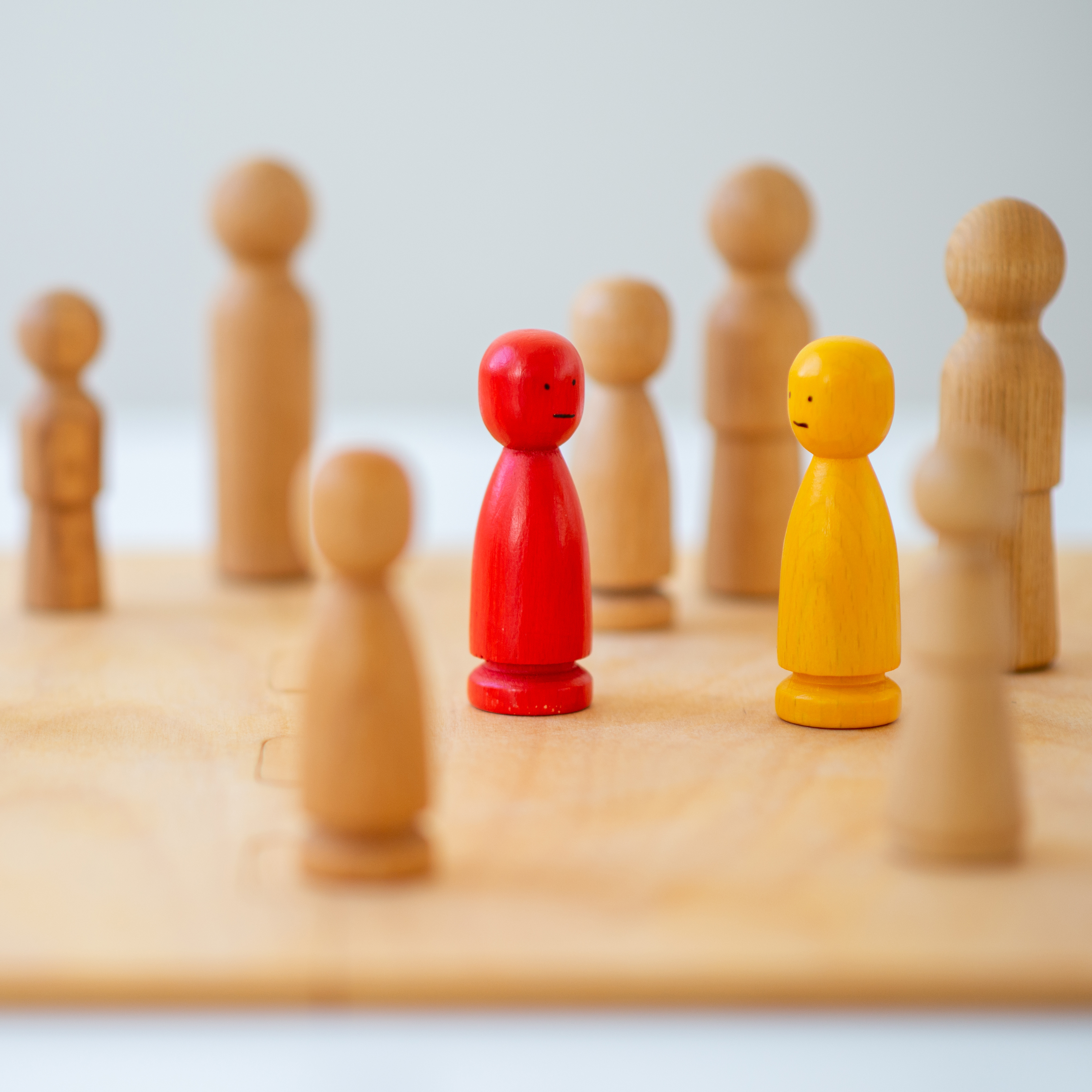Holzfiguren auf Spielfeld als Symbol für systemische Therapie, Familientherapie