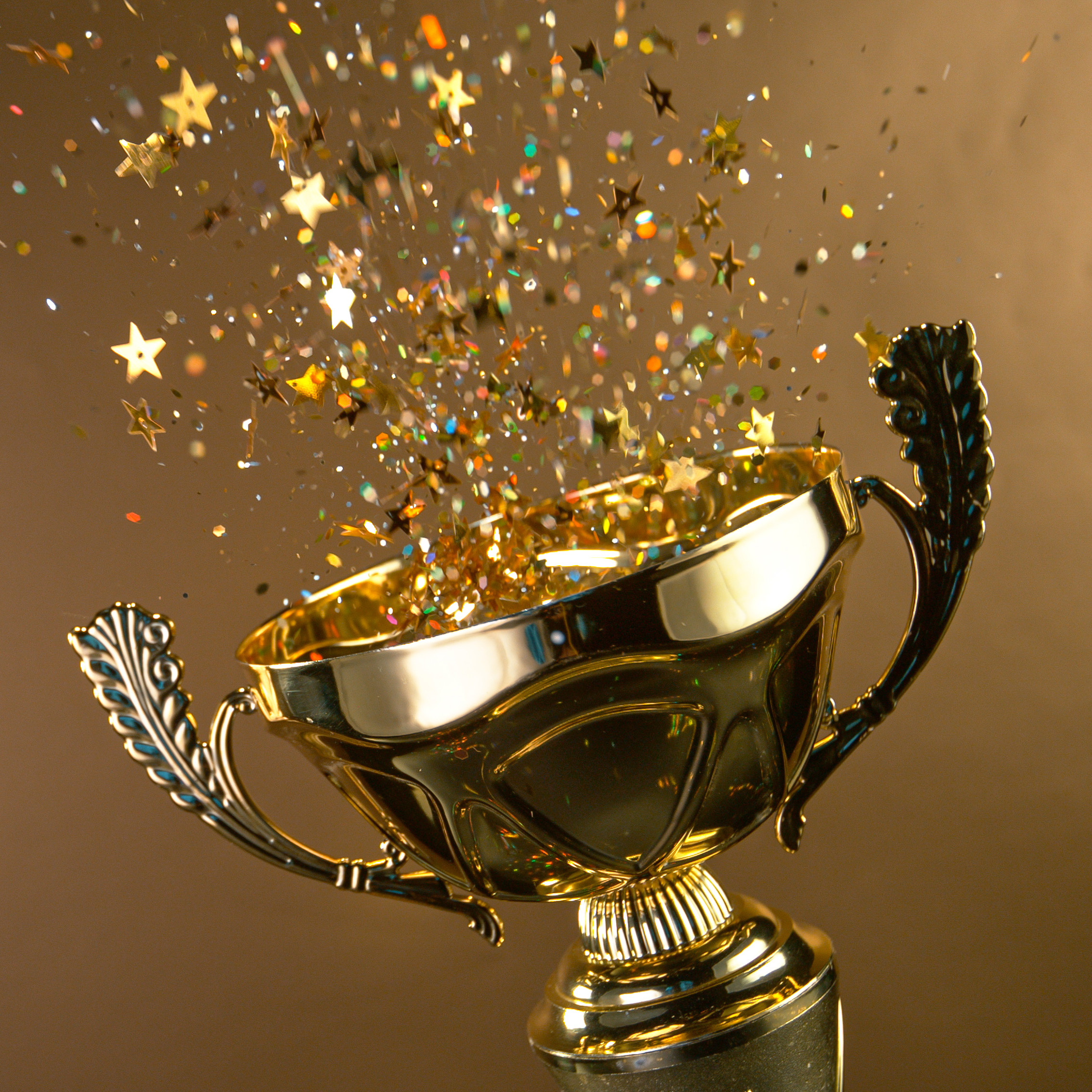 Ein Pokal aus dem Confetti sprüht auf goldenem Hintergrund
